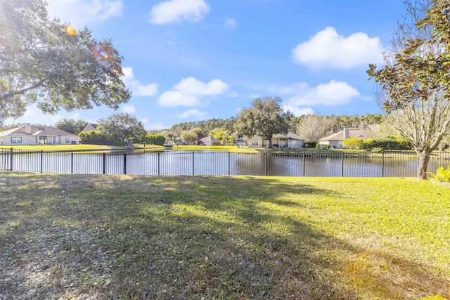 view of yard with a residential view, a water view, and fence