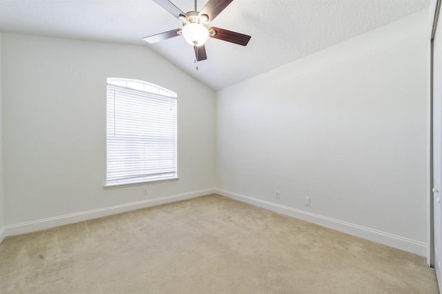 unfurnished room with vaulted ceiling, light colored carpet, baseboards, and ceiling fan