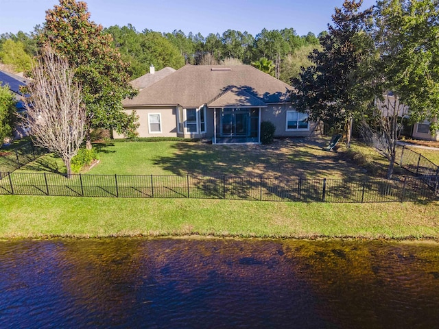 back of house with stucco siding, a water view, a yard, a sunroom, and fence private yard