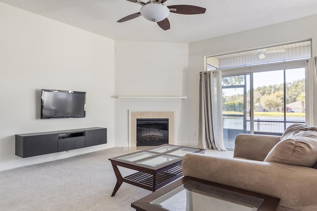 carpeted living room with a tiled fireplace, a textured ceiling, and ceiling fan