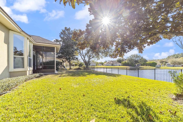 view of yard with a water view, a fenced backyard, and a sunroom