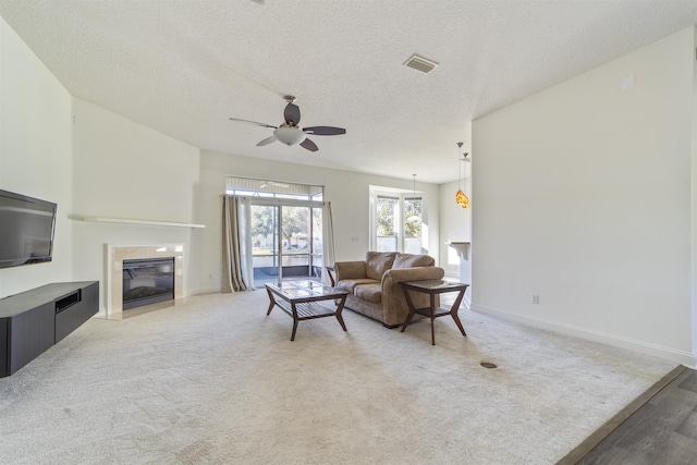 living area with a ceiling fan, baseboards, visible vents, a fireplace, and light carpet