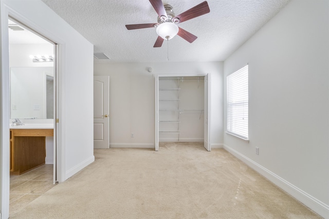 unfurnished bedroom with a closet, light carpet, a textured ceiling, and baseboards