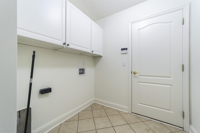 laundry room with hookup for a washing machine, light tile patterned floors, baseboards, cabinet space, and a textured ceiling