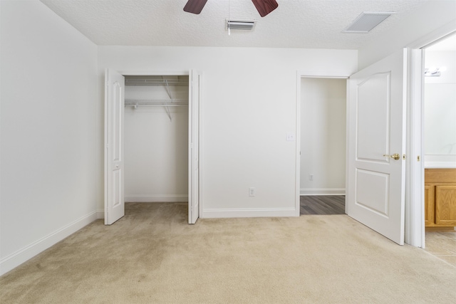 unfurnished bedroom featuring visible vents, light colored carpet, and a textured ceiling