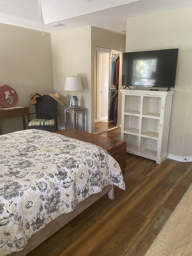 bedroom featuring visible vents, a walk in closet, baseboards, wood finished floors, and a closet