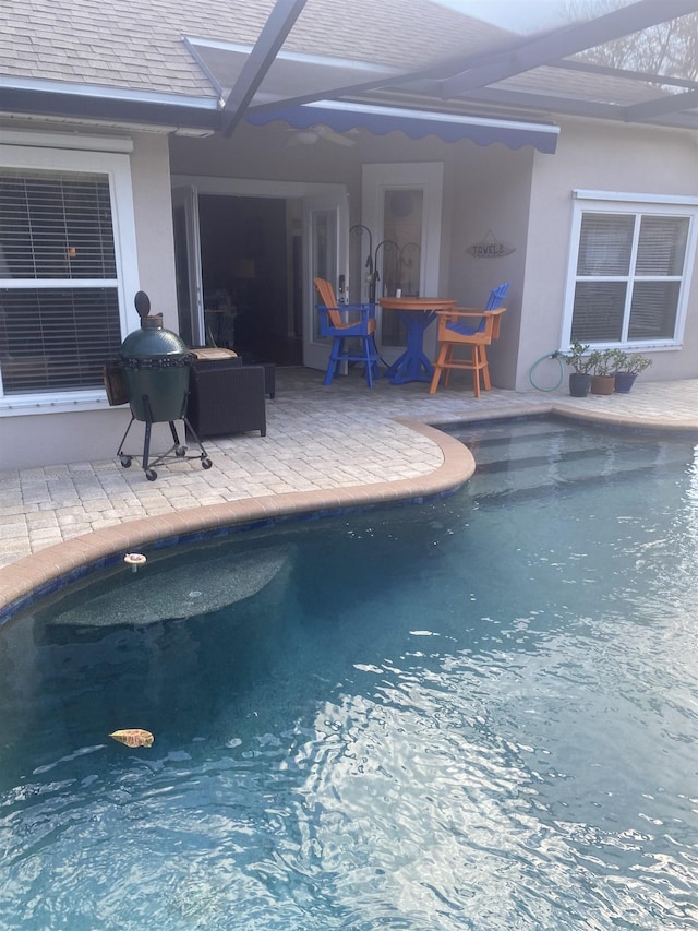 outdoor pool featuring a patio area, area for grilling, and glass enclosure