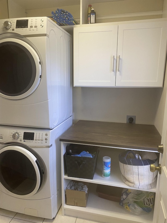 laundry room with stacked washer / dryer, light tile patterned floors, and cabinet space