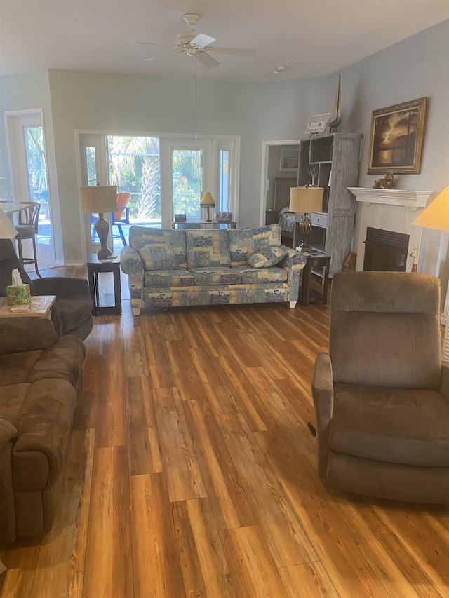 living room with a fireplace, a ceiling fan, and wood finished floors