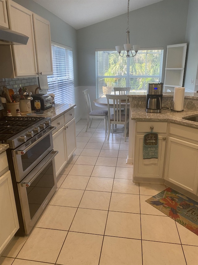 kitchen featuring double oven range, lofted ceiling, light tile patterned flooring, a notable chandelier, and a wealth of natural light