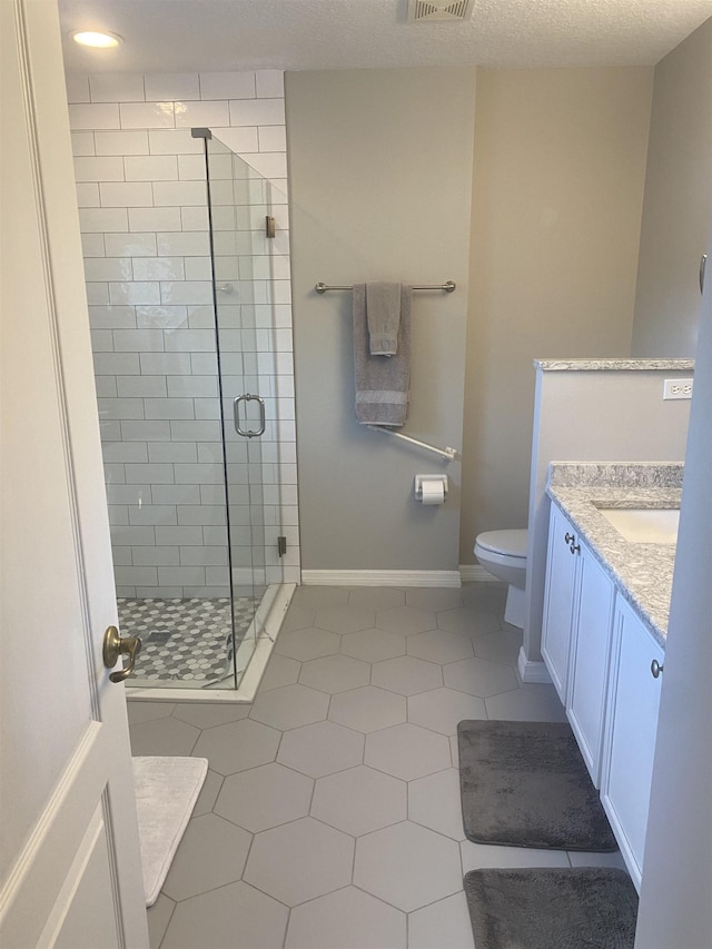 full bath with vanity, visible vents, baseboards, a shower stall, and toilet