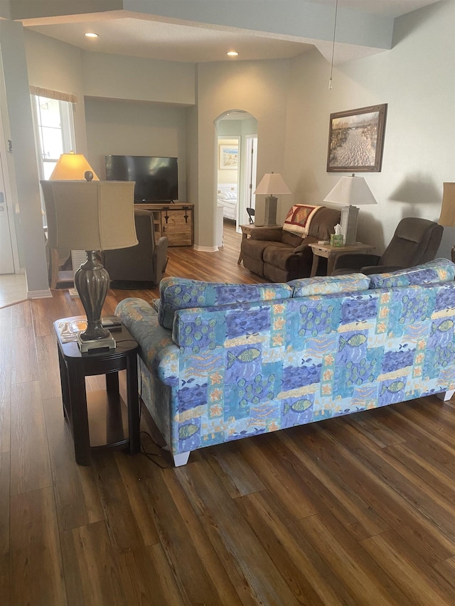 living room featuring recessed lighting, wood finished floors, arched walkways, and baseboards