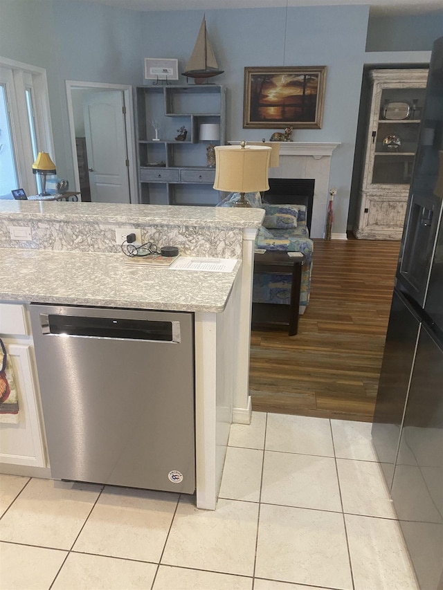 kitchen featuring dishwasher, light tile patterned floors, and a fireplace