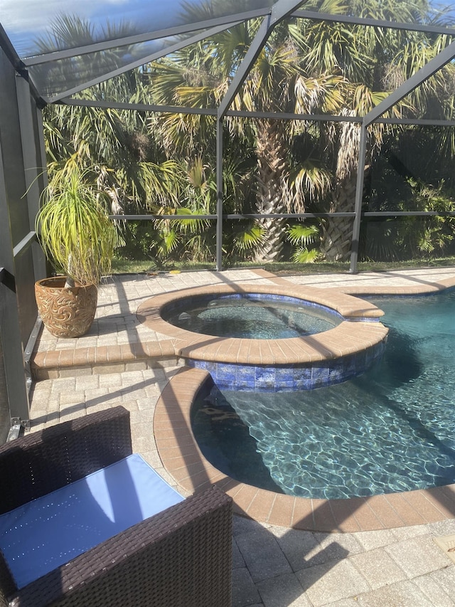 pool featuring a patio, an in ground hot tub, and a lanai