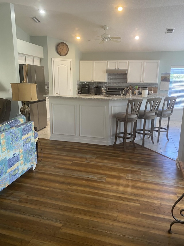 kitchen featuring freestanding refrigerator, ceiling fan, dark wood-type flooring, white cabinetry, and backsplash