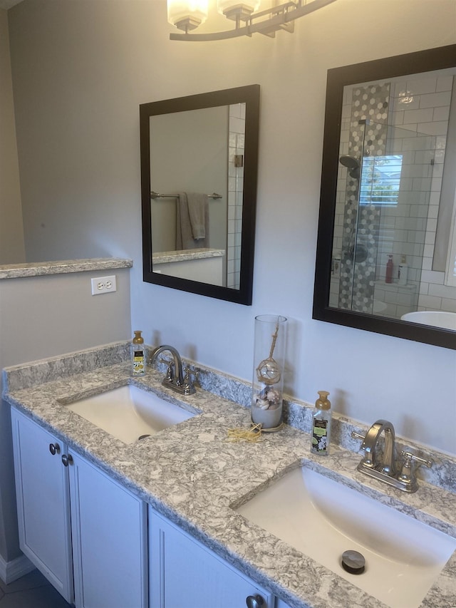 bathroom with double vanity, tiled shower, and a sink