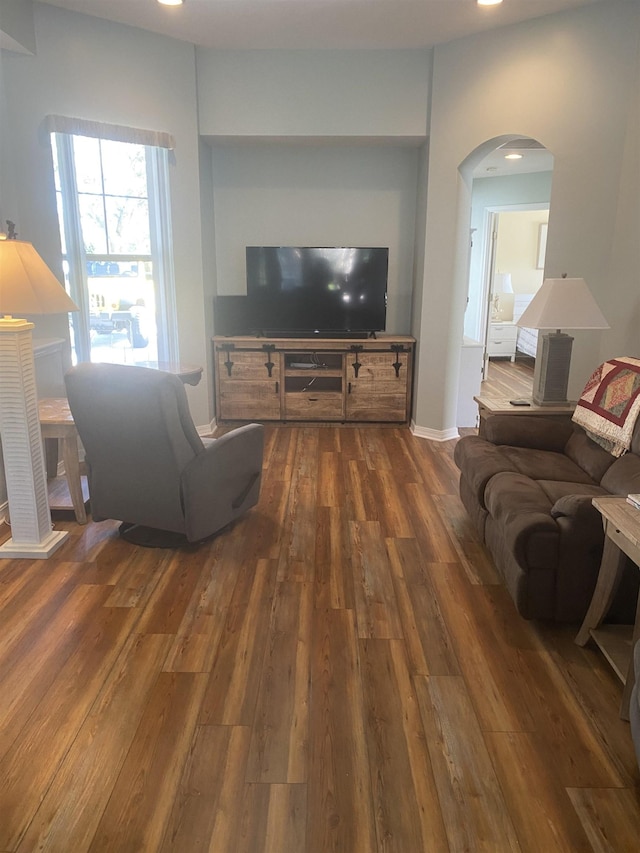 living area featuring arched walkways, recessed lighting, baseboards, and wood finished floors