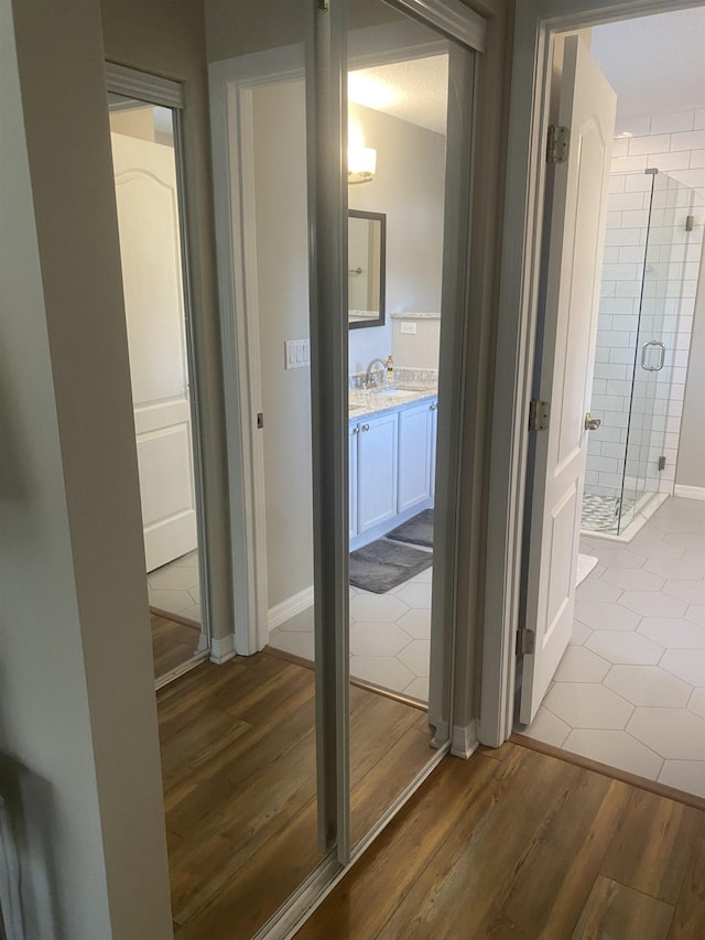 hall with dark wood-style floors, baseboards, and a sink