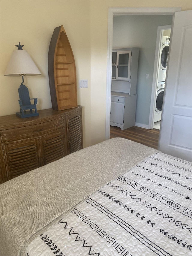 bedroom with stacked washer and clothes dryer and wood finished floors