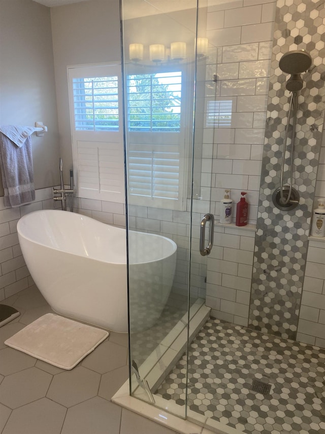 bathroom featuring tile walls, a stall shower, tile patterned floors, and a freestanding bath