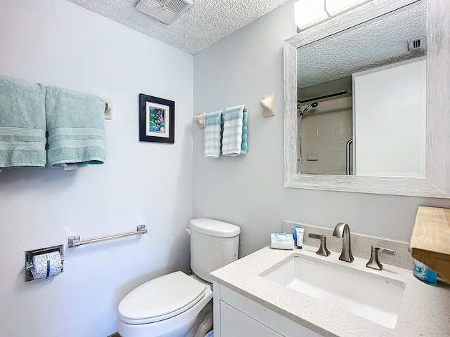 bathroom with vanity, toilet, a textured ceiling, and walk in shower