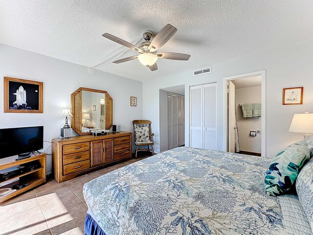 bedroom featuring ceiling fan, light tile patterned flooring, and a textured ceiling