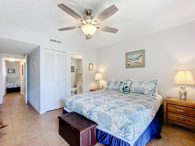 tiled bedroom with ensuite bath, ceiling fan, a closet, and a textured ceiling