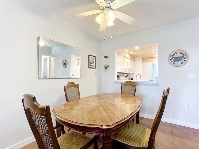 tiled dining area with a textured ceiling and ceiling fan