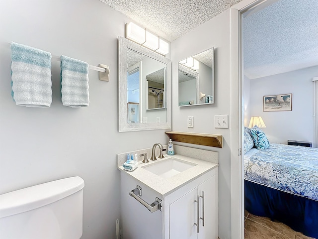 bathroom featuring tile patterned flooring, vanity, a textured ceiling, and toilet