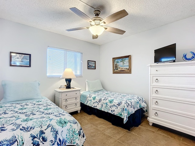 tiled bedroom with ceiling fan and a textured ceiling