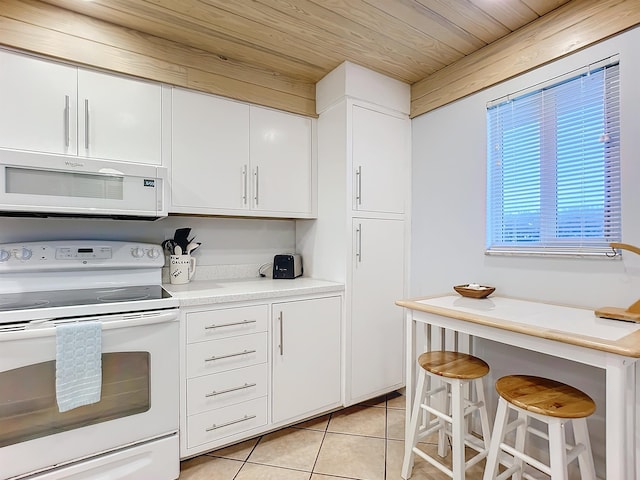 kitchen featuring white appliances, light tile patterned floors, a kitchen bar, white cabinetry, and wood ceiling