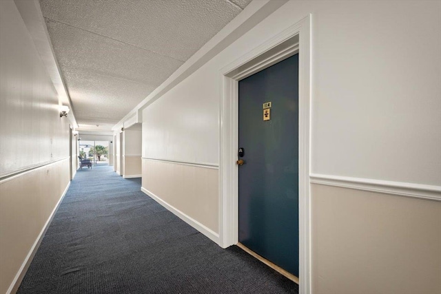 hall featuring carpet floors and a textured ceiling