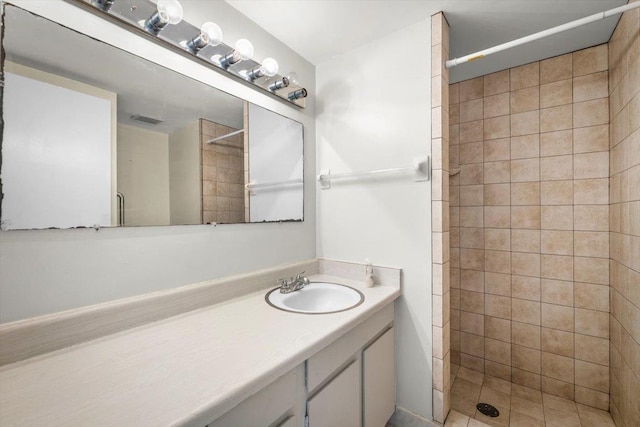 bathroom featuring tiled shower and vanity