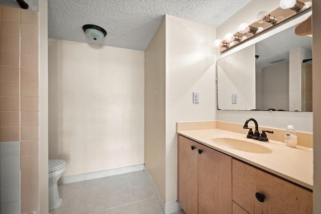 bathroom featuring tile patterned flooring, vanity, a textured ceiling, and toilet