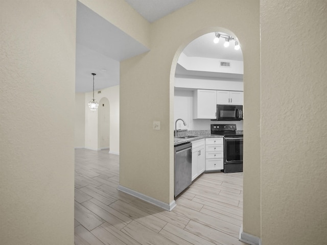 kitchen with black appliances, white cabinetry, sink, and hanging light fixtures