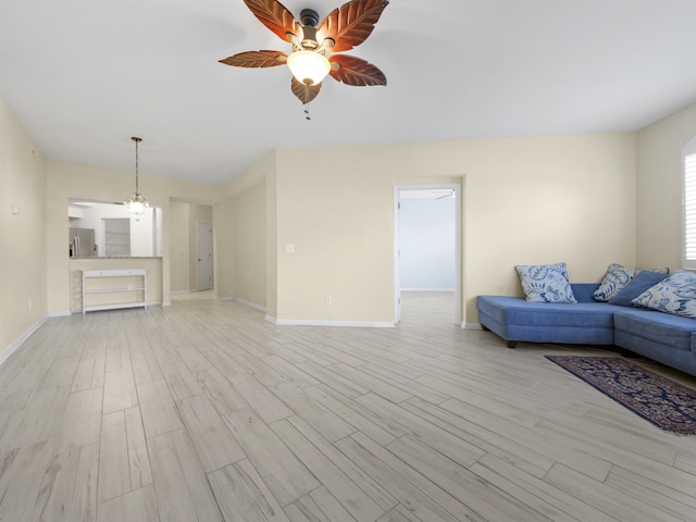 unfurnished living room featuring ceiling fan with notable chandelier and light wood-type flooring