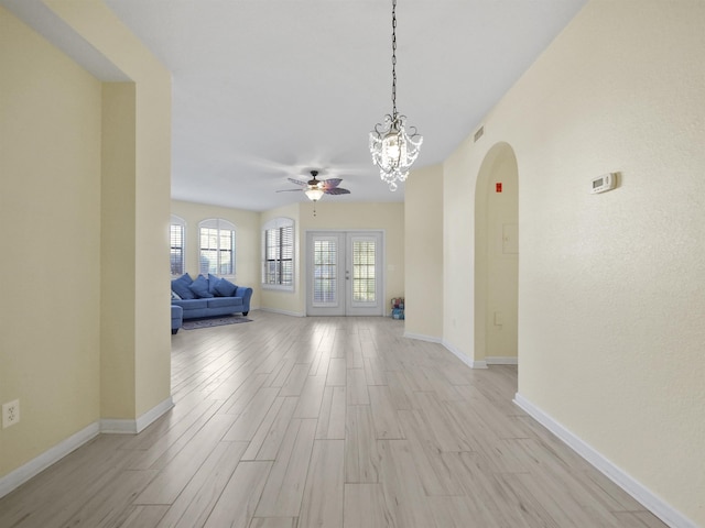 unfurnished room featuring ceiling fan with notable chandelier and light hardwood / wood-style floors