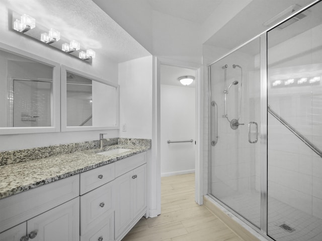 bathroom with hardwood / wood-style flooring, vanity, and a shower with door