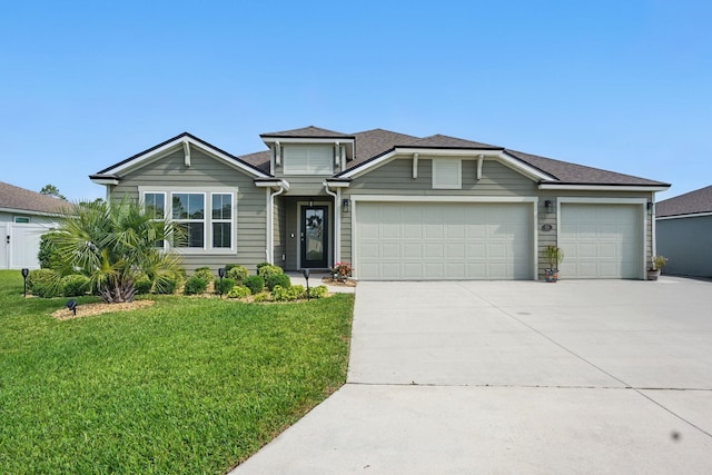 traditional-style home featuring concrete driveway, a front lawn, an attached garage, and roof with shingles
