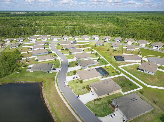 aerial view of property's location featuring a forest, a large body of water, and nearby suburban area