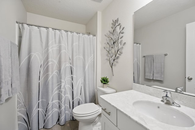 bathroom with toilet, vanity, and a textured ceiling