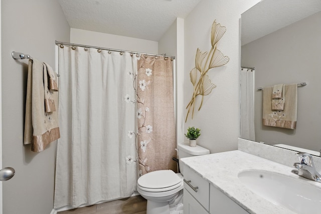 full bath featuring toilet, vanity, a textured ceiling, and wood finished floors