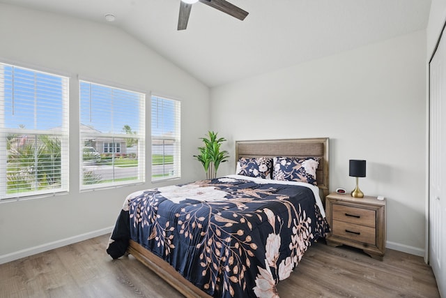 bedroom featuring multiple windows, vaulted ceiling, wood finished floors, and baseboards