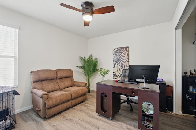 home office with light wood-style floors, ceiling fan, and baseboards