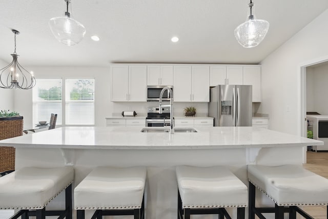 kitchen featuring stainless steel appliances, a sink, white cabinets, decorative light fixtures, and recessed lighting