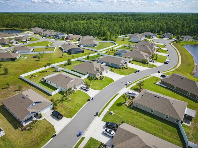 aerial perspective of suburban area featuring a heavily wooded area and a large body of water