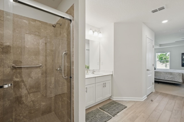 bathroom featuring wood finished floors, connected bathroom, a stall shower, recessed lighting, and vanity