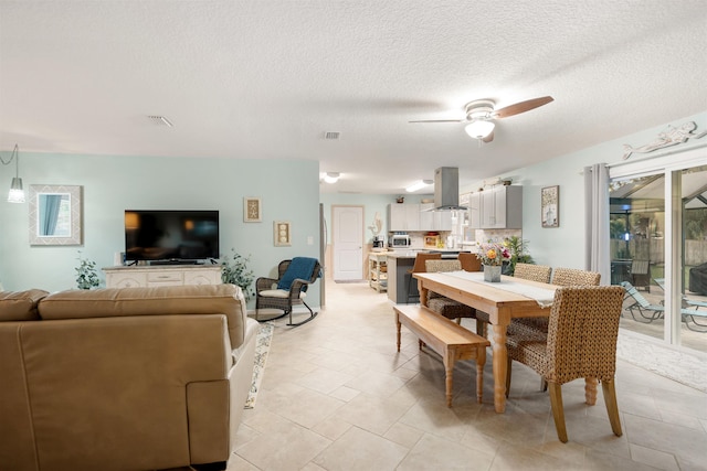 tiled dining area with ceiling fan and a textured ceiling