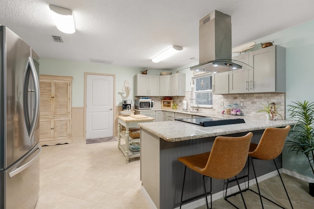 kitchen with island exhaust hood, kitchen peninsula, gray cabinets, and appliances with stainless steel finishes