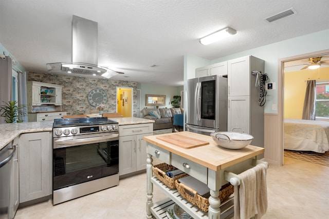 kitchen with wall chimney range hood, wood counters, a textured ceiling, gray cabinets, and appliances with stainless steel finishes